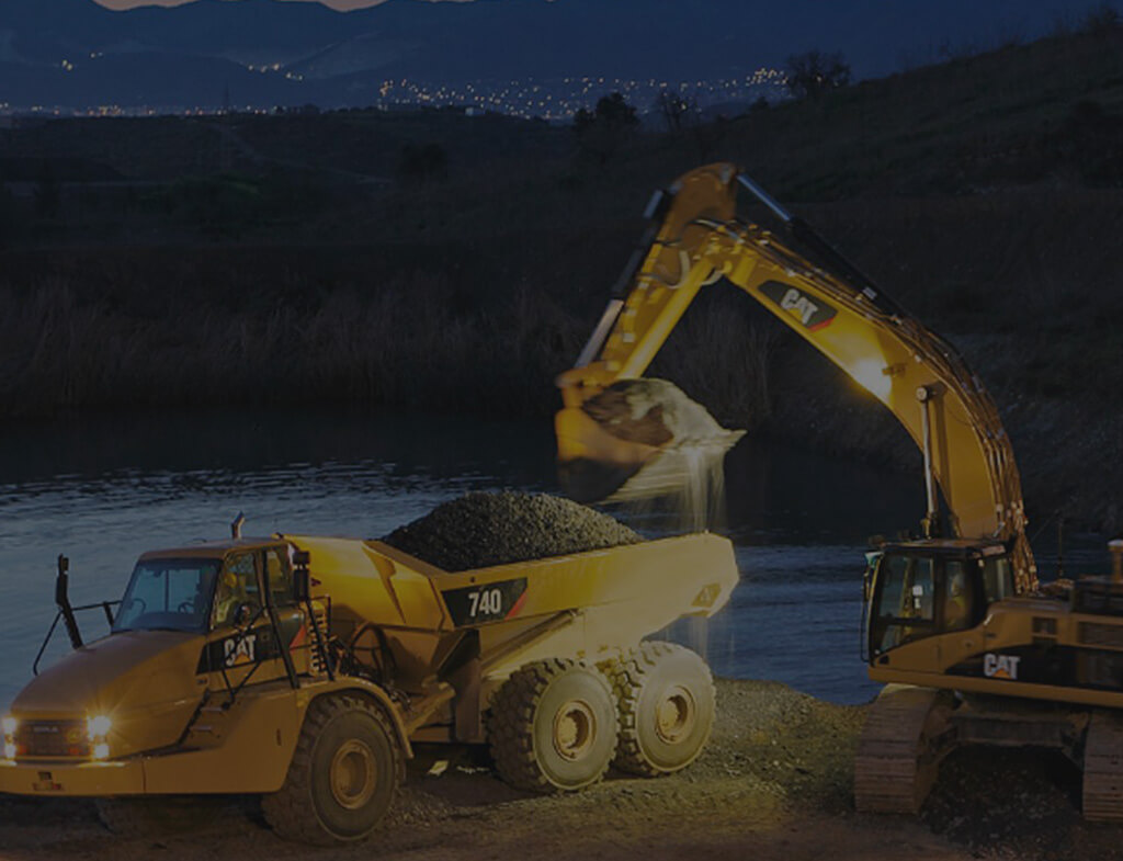 Chantien de construction la nuit avec excavatrice, camion benne et bulldozer