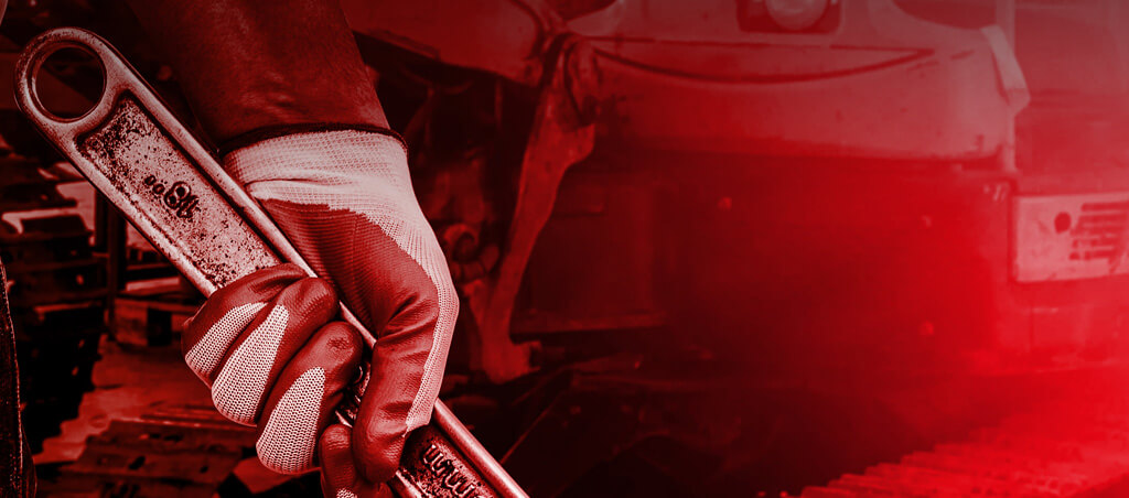 Mécanicien diesel tenant une clé devant un camion en réparation dans un garage