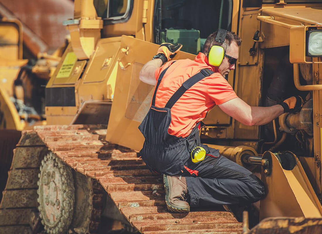 Mécanicien diesel effectuant l'entretien d'une machinerie lourde(excavatrice/bulldozer) sur un chantier